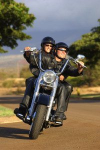 A couple rides their motorcycle on a curvy road toward the viewer.